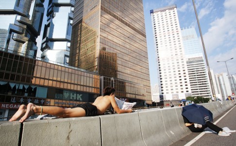 A protester reads a paper while catching some sun on a concrete island along Connaught Road in Admiralty. Photo: Dickson Lee