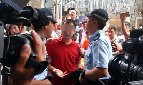 A man (centre, with face partially blurred) is questioned by police and later escorted away from Mong Kok after demonstrators alleged he took an upskirt photo of a protester. Photo: Thomas Chan