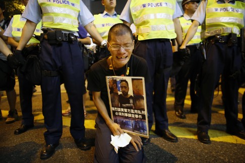 A pro-democracy protester cries as he holds a placard with photos of Ken Tsang during a rally in front of the police headquarters in Wan Chai. Photo: Reuters