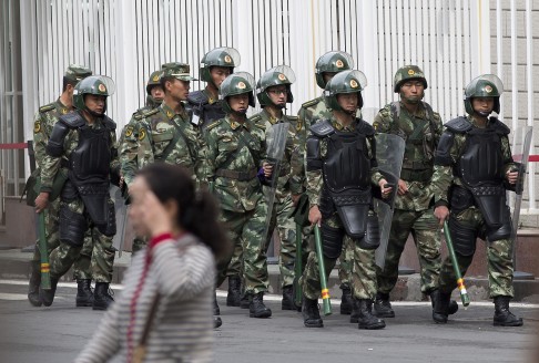 Paramilitary policemen with shields and batons patrol near the People's Square in Urumqi, Xinjiang region. Photo: AP