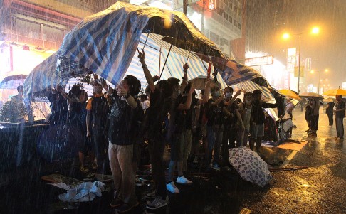 Protesters take cover as a downpour hits Mong Kok. Photo: Dickson Lee
