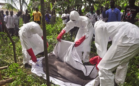 Hearth workers cover the body of a man suspected of dying from the Ebola virus on the outskirts of Monrovia, Liberia on Friday. Photo: AP