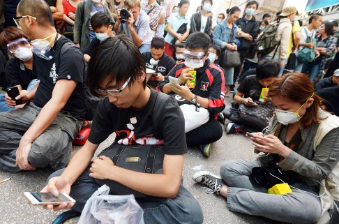 Protesters check their smartphones. Photo: Kyodo News