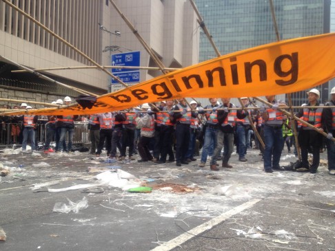 An iconic banner reading 'It's just the beginning' is pulled down by clean-up crews. Photo: Alan Yu