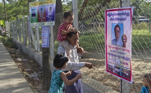 A father and his children look at a candidate's poster at a polling station in Dala township. Photo: AP