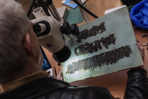 David Blank, professor of Classics from University of California, looks through a microscope at an ancient papyrus to decipher the writing. Photo: AP
