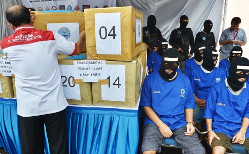 Members of an international drug syndicate led by Hong Kong drug lord Wong Chi Ping (front row, second right) sit next to boxes containing some of the 862kg of Ice before they are destroyed by National Narcotics Agency at a ceremony in Tangerang, Jakarta. Photo: AFP