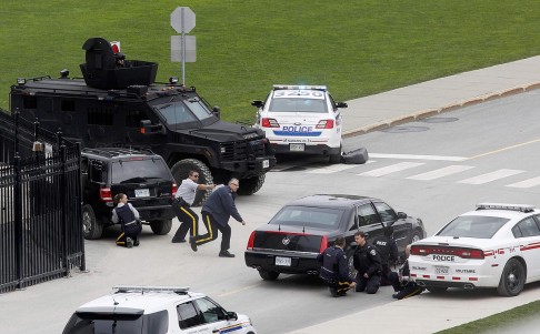 officers take cover near the Ottawa's Canadian War Memorial following the 2014 shooting. Photo: Reuters