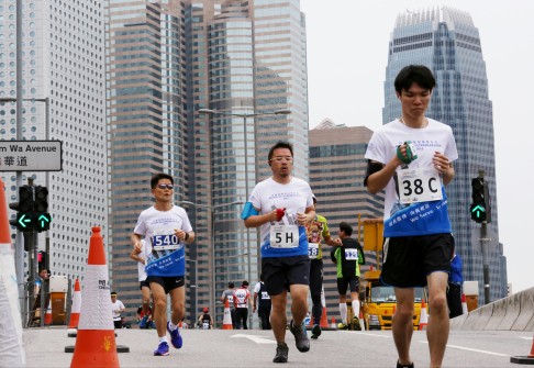Runners make their way along the course of the Rotary HK Ultramarathon in Lung Wo Road, Central. 