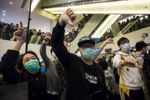 Protesters give thumbs-down signs to mainland Chinese travellers during a demonstration inside a shopping mall. Photo: Reuters