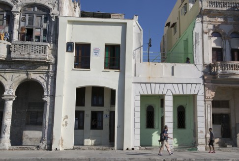 Tourists walk beside two privately owned houses with rooms for rent in Havana. Photo: AP