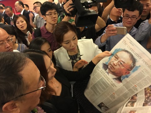 Liu Chuanzhi and other VIPs read a feature on the Chinese businessman in the South China Morning Post at Legend Holding's HKEX debut ceremony. Photo: Bien Perez