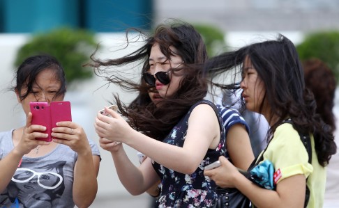 Tourists check their mobile phones amid windy conditions after the No8 signal was issued yesterday. Photo: Dickson Lee