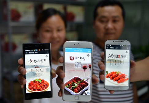 A couple in China's Jiangsu province show an advertisement for their online crayfish business on WeChat, the predominant free messaging app on the Chinese mainland. Photo: Xinhua
