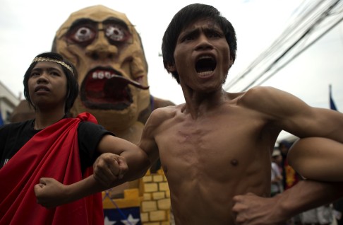 Activists march near the house of Philippine President Benigno Aquino with an effigy (background) depicting Aquino as a monster, in Manila one day ahead of Aquino's State of the Nation address. Photo: AFP