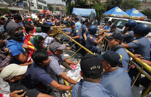 Police hold back protesters as they push barricades near the home of the family of Philippine President Benigno Aquino during a rally in suburban Quezon city north of Manila. Demonstrators are protesting Aquino ahead of his State of the Nation address on Monday. Photo: AP 