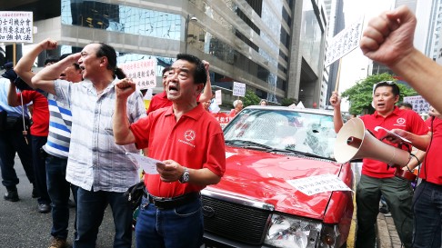 Taxi drivers smash a taxi to call on the government to ban car-rental service on July 24, 2015. Photo: Dickson Lee