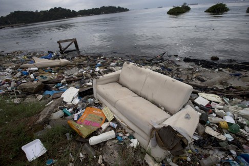 In this June 1, 2015 file photo, a discarded sofa litters the shore of Guanabara Bay in Rio de Janeiro, Brazil. As part of its Olympic bid, Brazil promised to build eight treatment facilities to filter out much of the sewage and prevent tons of household trash from flowing into the Guanabara Bay. Only one has been built. Tons of household trash line the coastline and form islands of refuse. (AP Photo/Silvia Izquierdo, File)
