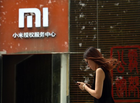 A woman walks past a Xiaomi service center in Beijing. The logo looks similar to the one used by iMI. Photo: AFP