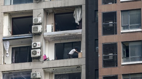 A victim of the explosions collects belongings at his damaged home. Photo: AFP