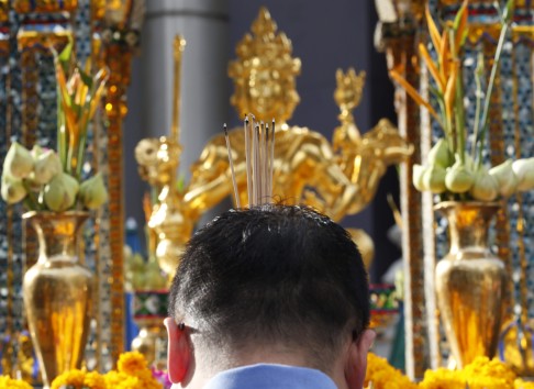 A man burns joss stick at a statue of Lord Brahma, the Hindu God of Creation, at the Erawan Shrine in Bangkok. Photo: EPA