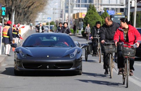 Flouting the rules: cyclists look at an illegally parked Ferrari in Beijing. Photo: AFP
