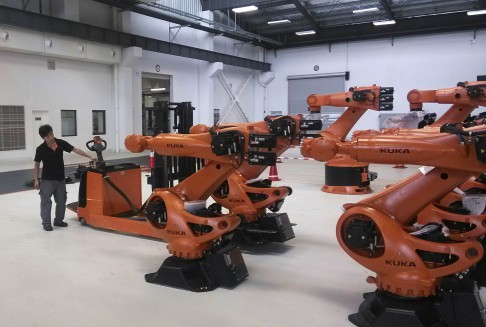 A staff member stands next to robots at a plant of Kuka Robotics in Shanghai. Photo: Reuters