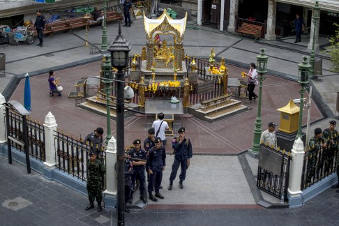 Thai police stand guard as people pray during a crime re-enactment near the bomb site. Photo: Reuters