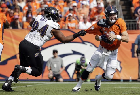 Baltimore Ravens defensive tackle Carl Davis, left, pulls on the jersey of Denver Broncos quarterback Peyton Manning. Photo: AP