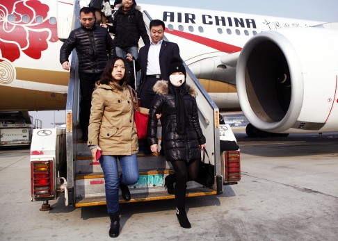 An alleged Chinese  'economic fugitive', wearing a mask, arrives back in China after 10 years on the run in Italy. Photo: SCMP Pictures