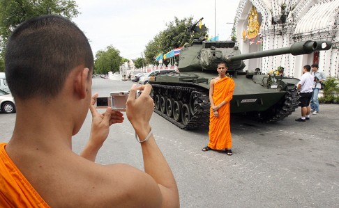 A Buddhist monk poses for pictures next to a tank at the Marble Temple in Bangkok two days after a bloodless coup in September 2006. File photo: AFP