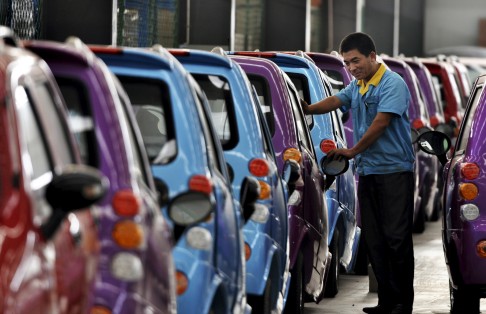 An employee checking newly-assembled electric cars at a factory in China's Shandong province. Photo: Reuters