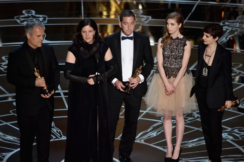 Laura Poitras, Glenn Greenwald, and Dirk Wilutzky receive the Oscar for best documentary feature at the 2015 Academy Awards. Photo: AFP