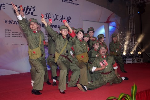 Airport staff in Shenzhen, Guangdong province, perform as Red Guards while holding red envelopes instead of Chairman Mao's famous little red book. Photo: Li Zhengde