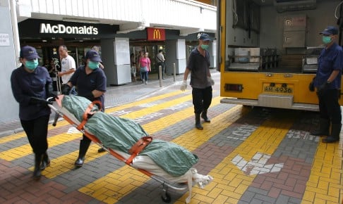 Workers remove the body of the woman, aged between 50 and 60, from the McDonald's outlet at Ping Shek Estate in Kowloon Bay. Photo: SCMP Pictures