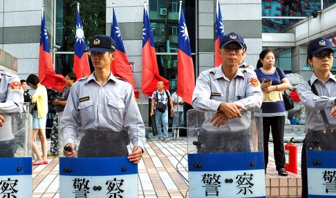 Taiwanese police force stand guard as supporters of Taiwan's ruling KMT party's presidential candidate, Hung Hsiu-chu, denounce the KMT for wanting her to step down. Photo: EPA