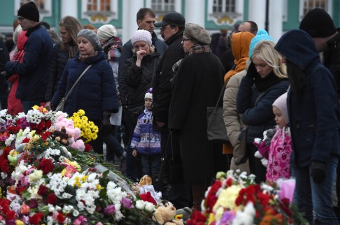 People stand snext to flowers at a makeshift memorial for the victims in St Petersburg. Photo: AFP