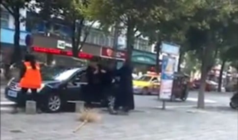 Suit-clad man pummels woman street sweeper on central China