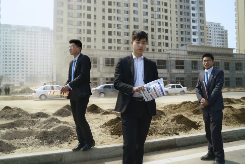 Estate agents, whose parents were once farmers, wait for clients near a new development built on former farmland on the outskirts of Beijing.