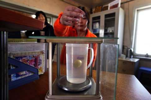 A woman performs a water displacement test to determine the purity of some gold that was brought in by small-scale miners at a processing plant north of Ulan Bator. Photo: Reuters