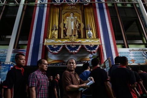 A portrait of Thai King Bhumibol Adulyadej stands above people queueing to vote at a polling station during the constitutional referendum in Bangkok. Photo: AFP