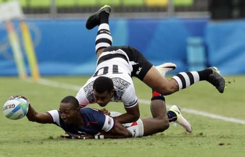 USA’s Perry Baker passes the ball back under pressure from Fiji’s Samisoni Viriviri. Photo: AP