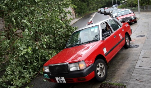 A taxi is working its way around a fallen tree in Tai Hang Road, Hong Kong Island after Typhoon Vicente hit the city last night. 24JUL12