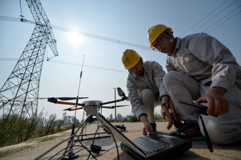 Workers adjust a quad-rotor drone in front of a transmission tower to check ultra-high voltage (UHV) power lines in central China's Hunan Province last week. For the first time, the Hunan Branch of the State Grid Corporation of China is using drones equipped with infrared camera to inspect its power lines. Photo: Xinhua