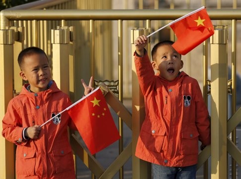 Twins Sun Qiyu and Sun Qichun wave China's national flags at the Tiananmen Gate in Beijing. Photo: Reuters