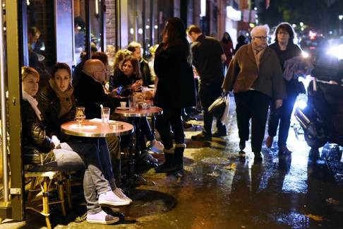 People have a drink outside a bar in the 11th arrondissement of Paris in defiance of the attacks that killed 129 people. Photo: AFP