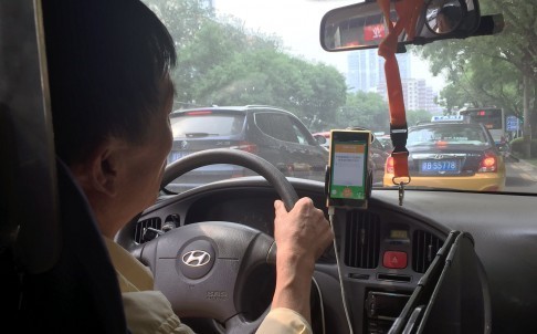 A taxi driver in Beijing takes a request from a taxi-hailing app. The new service from Didi Kuaidi promises to pair passengers travelling the same route over China’s Spring Festival. Photo: Simon Song