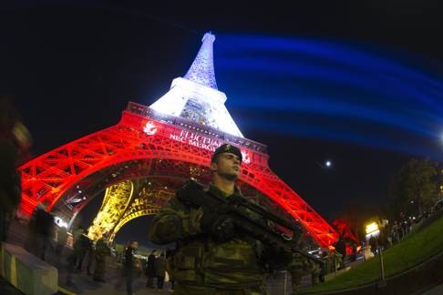 A French soldier in front of the Eiffel Tower, which is illuminated with the colours of the French national flag in tribute to the victims of the November 13 terror attacks. Photo: AFP
