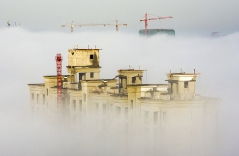 Cranes and residential buildings under construction are seen among thick fog in Anyang, Henan province. The physical manifestation of China’s overinvestment is its empty buildings and industrial overcapacity. Photo: Reuters
