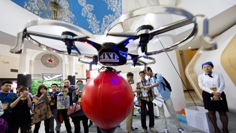 Visitors to the China Hobby Expo in October watch a drone controlled by a mobile phone fly in Beijing. Unmanned and remote-controlled aerial vehicles are gaining in popularity as prices drop and capabilities grow. Photo: AP